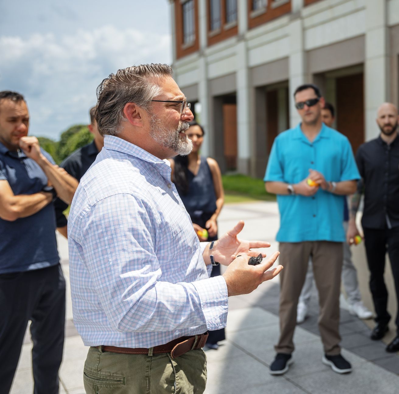 A man with glasses and a beard is talking to a group of people
