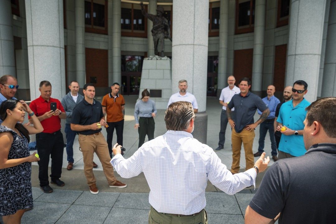 A group of people are standing in a circle in front of a building.