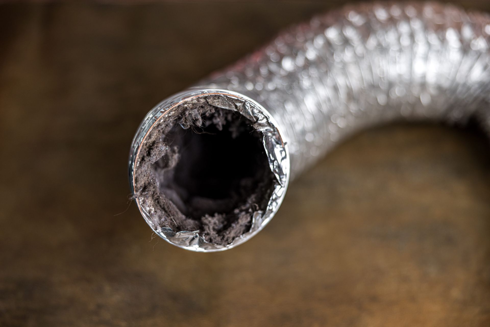Close-up of a clogged dryer vent hose with thick, dark lint buildup inside.