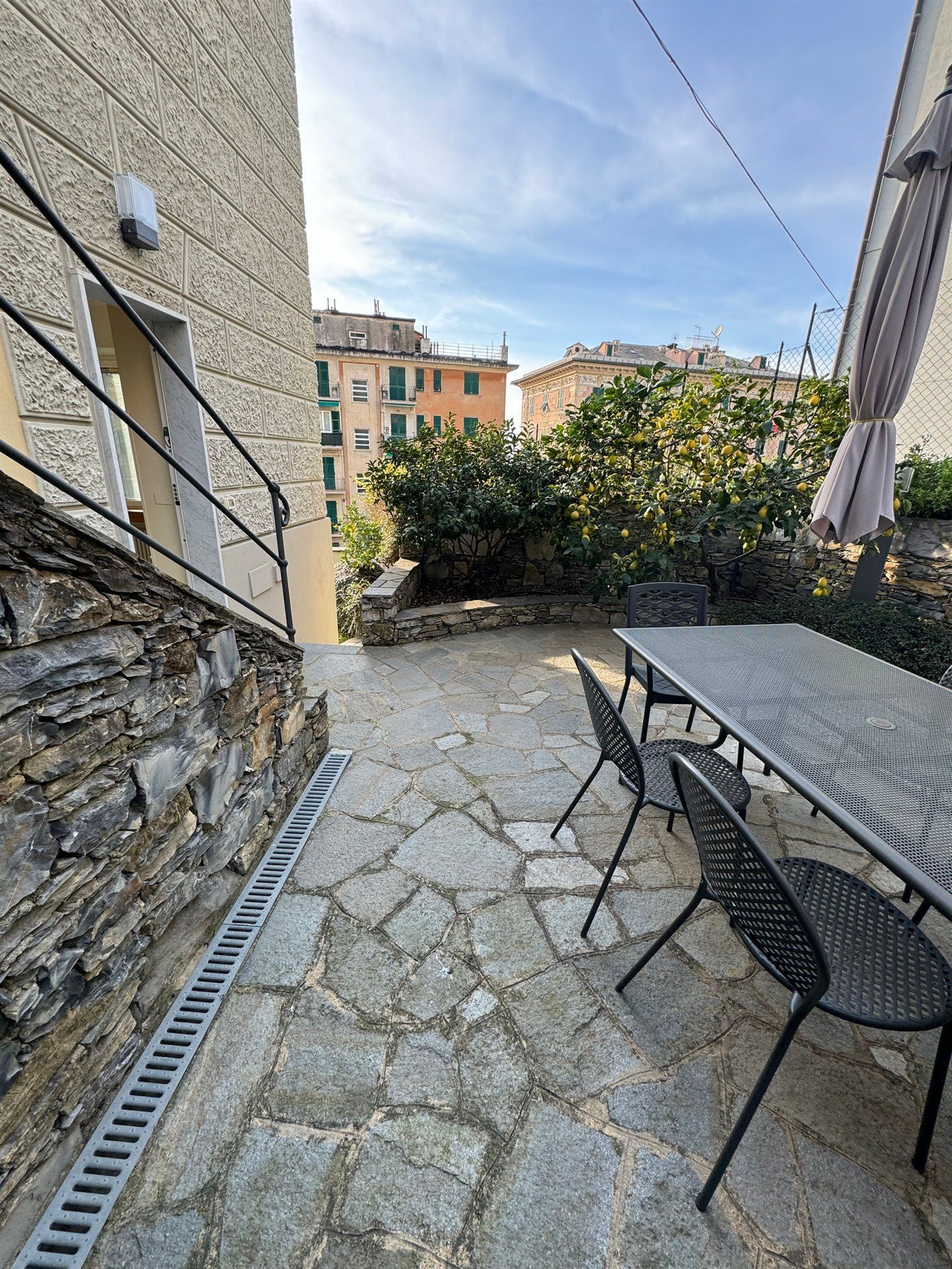 A stone patio with a table and chairs in front of a building.