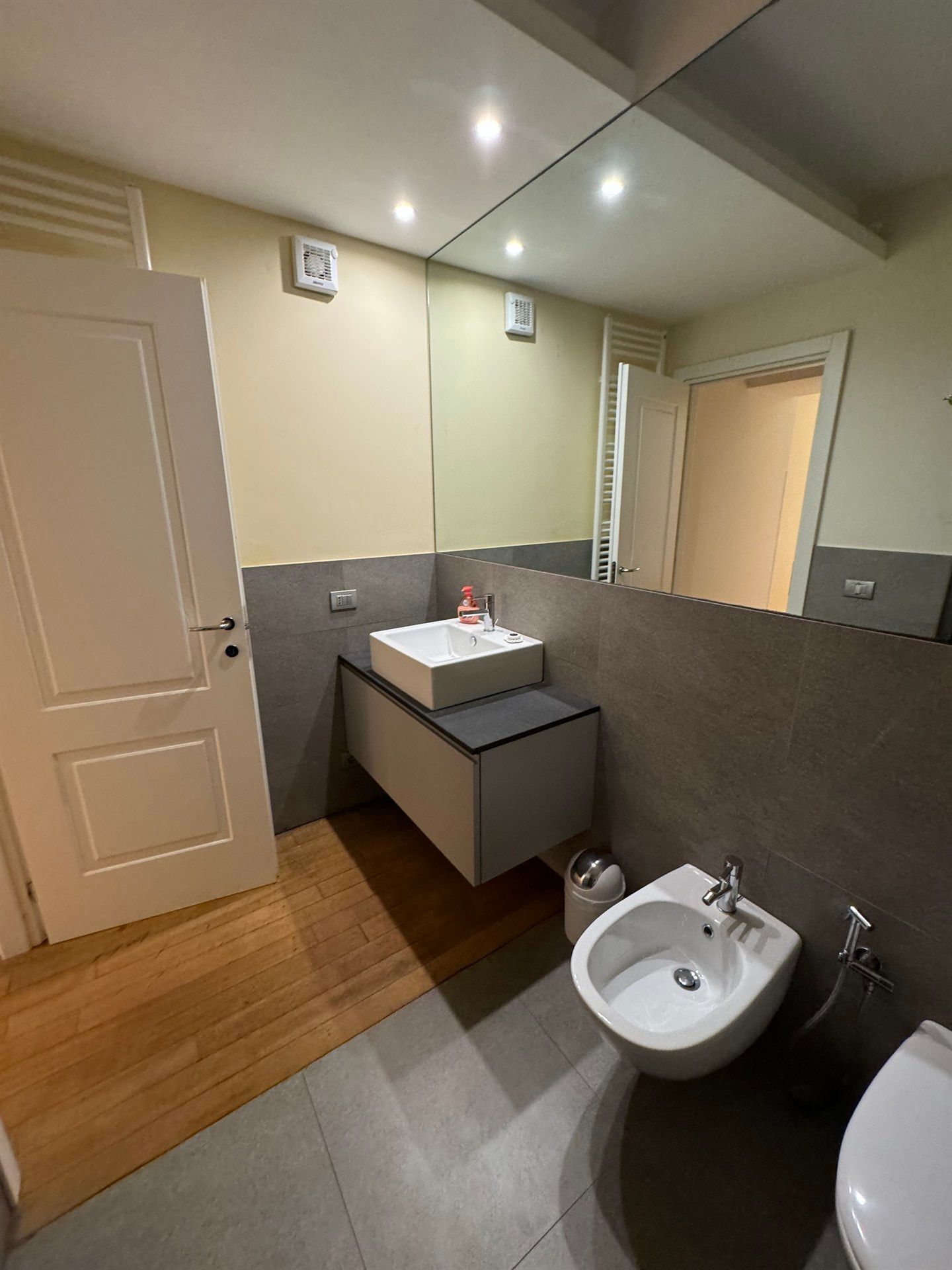 A bathroom with a sink , toilet , bidet and mirror.