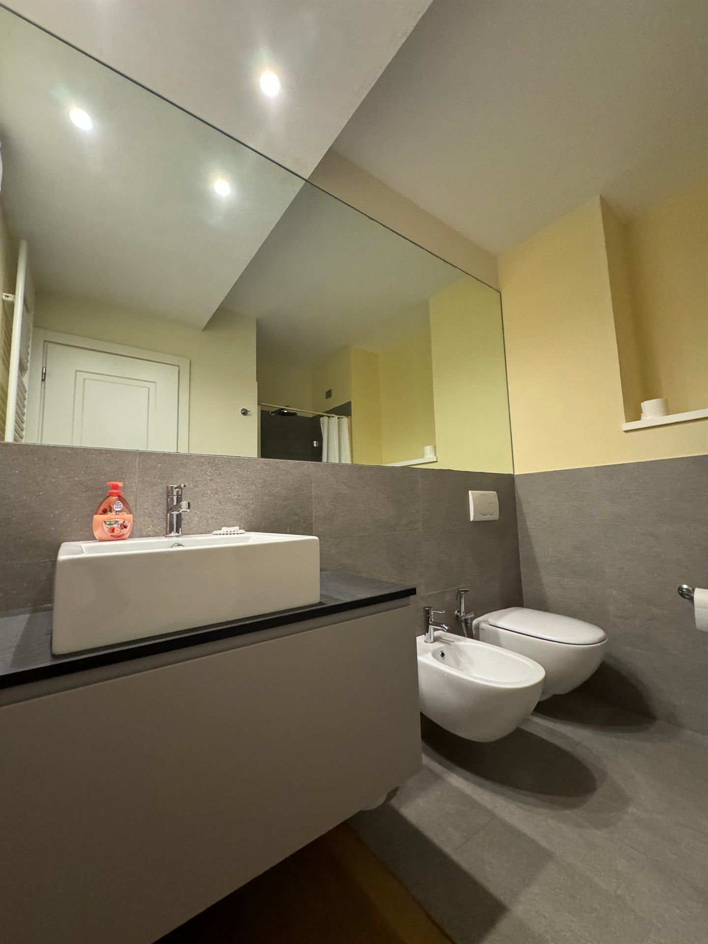 A bathroom with two toilets , a sink and a mirror