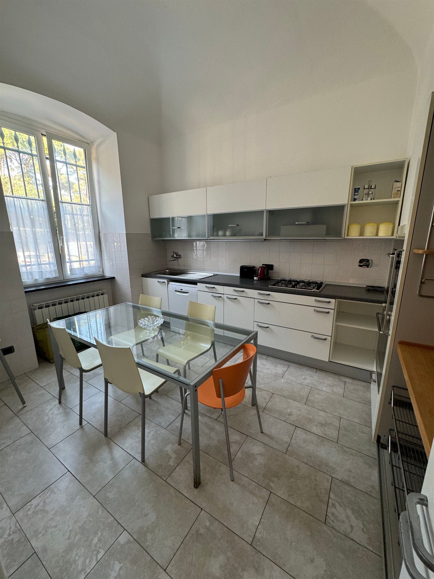 A kitchen with a glass table and chairs in it.