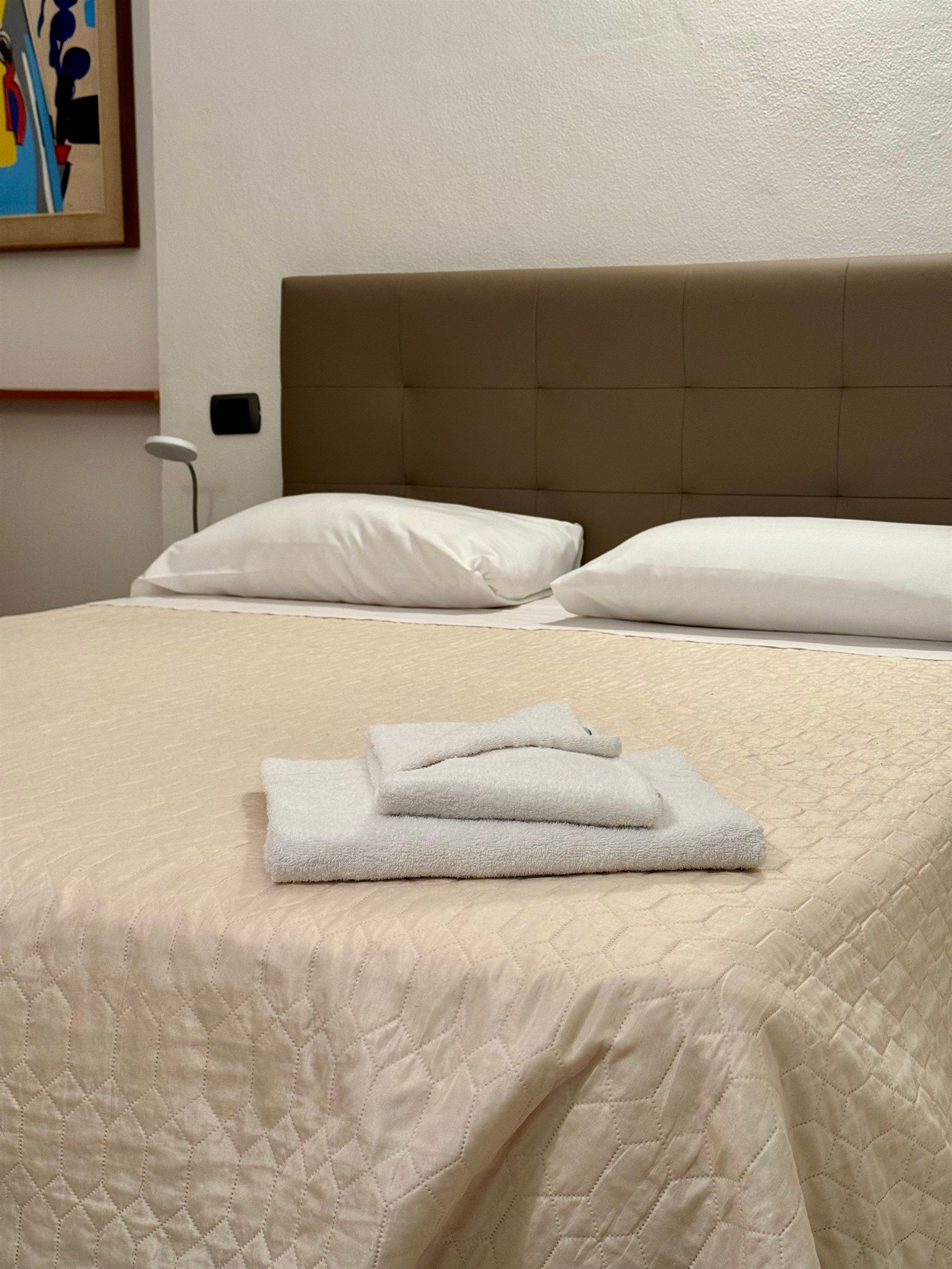 A bed with two pillows and two towels on it