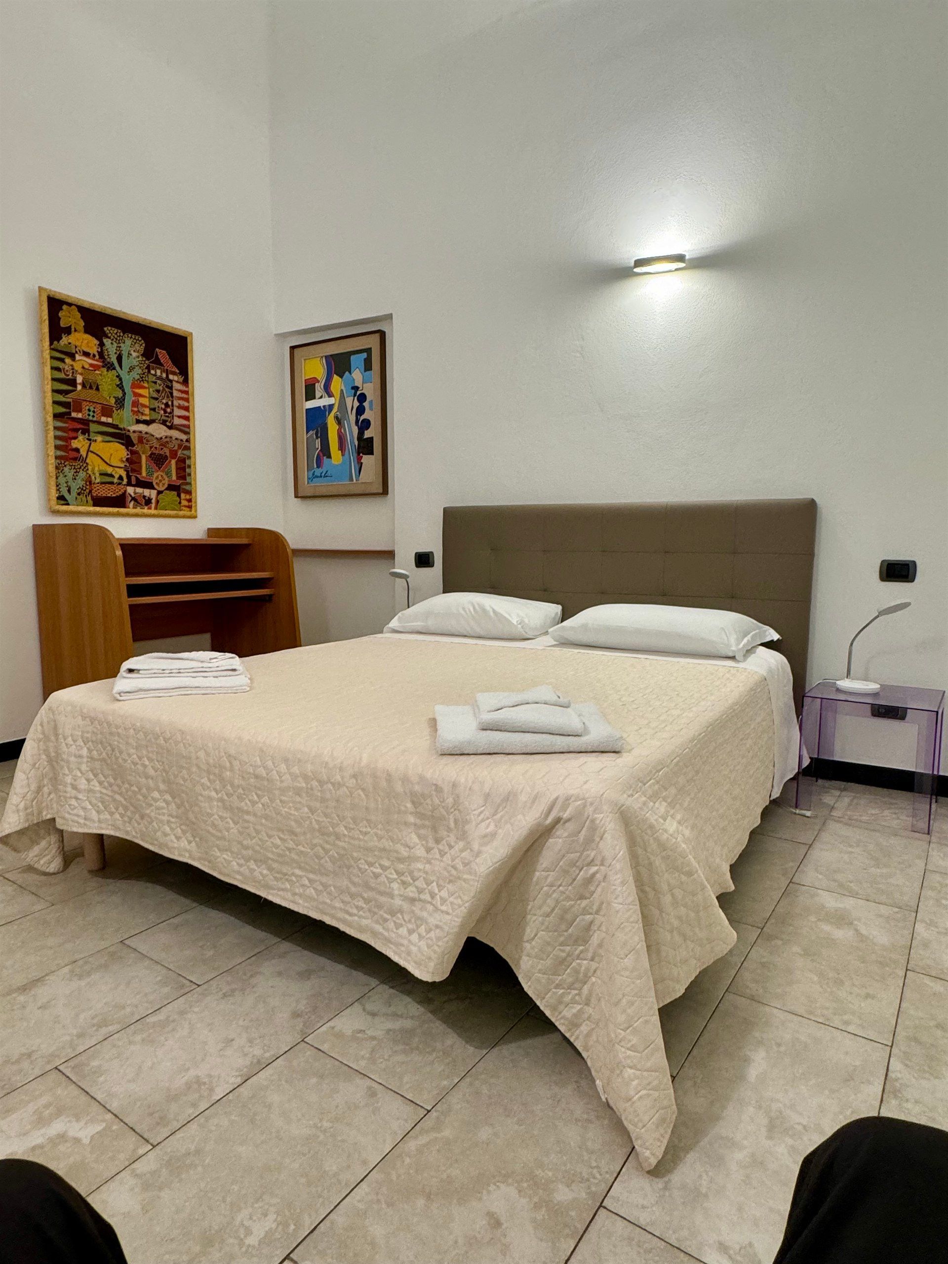 A bedroom with a large bed and a desk