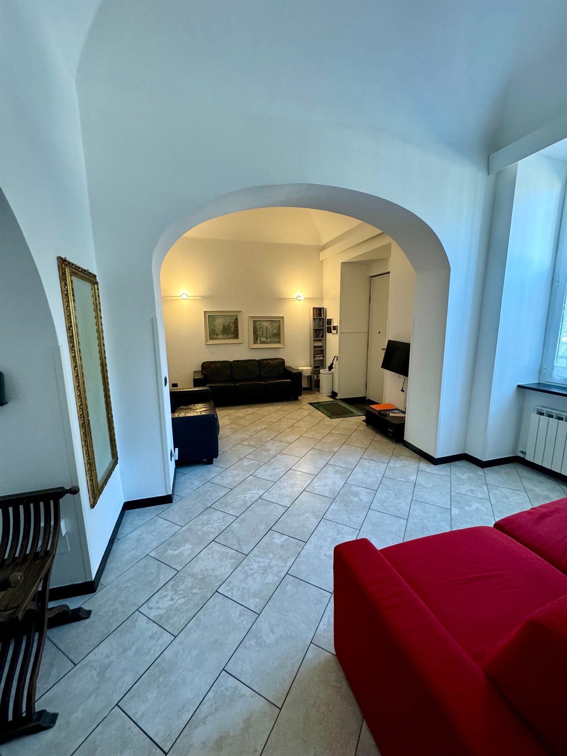 A living room with a red couch and a black couch