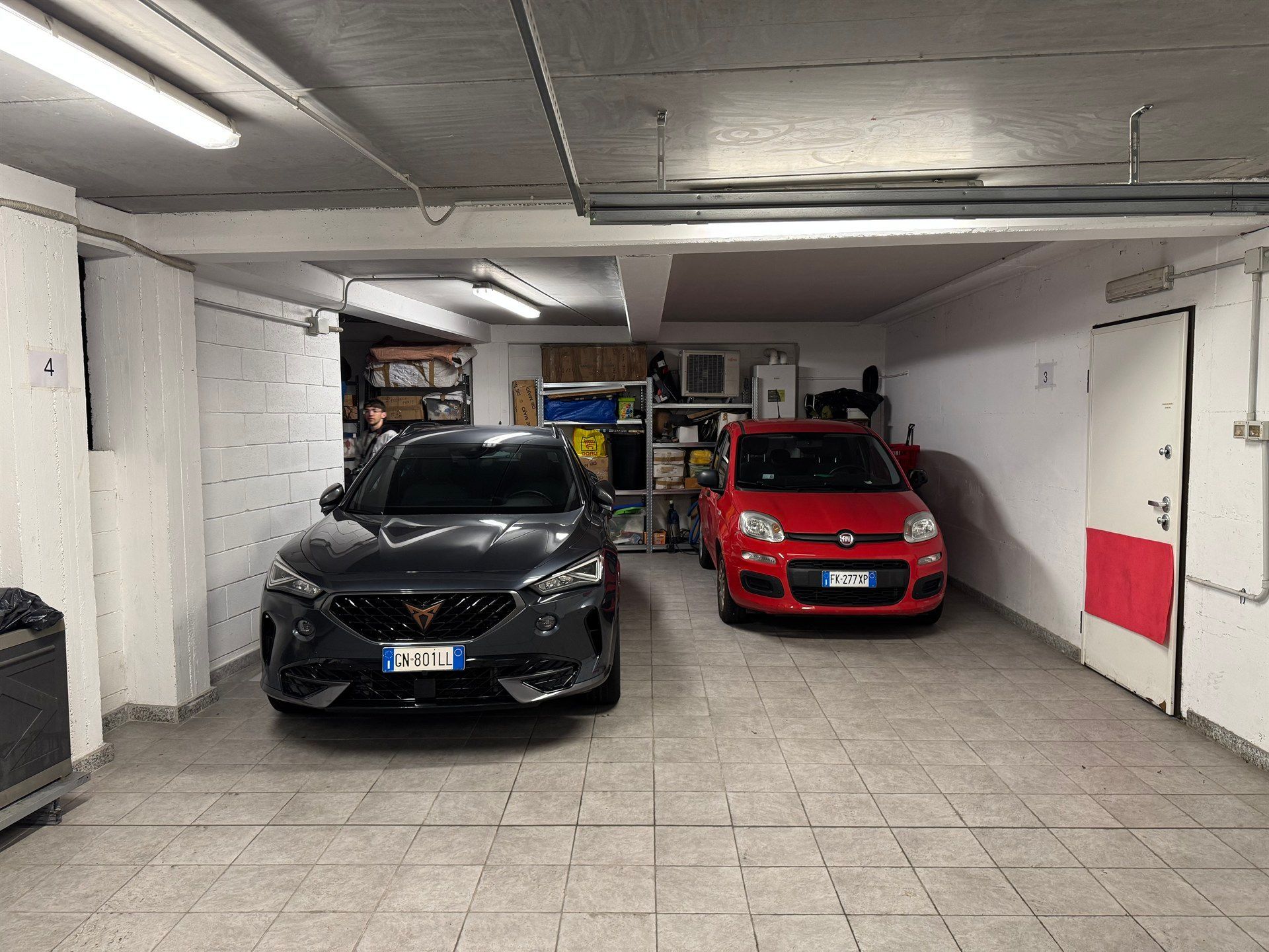 Two cars are parked in a garage next to each other.