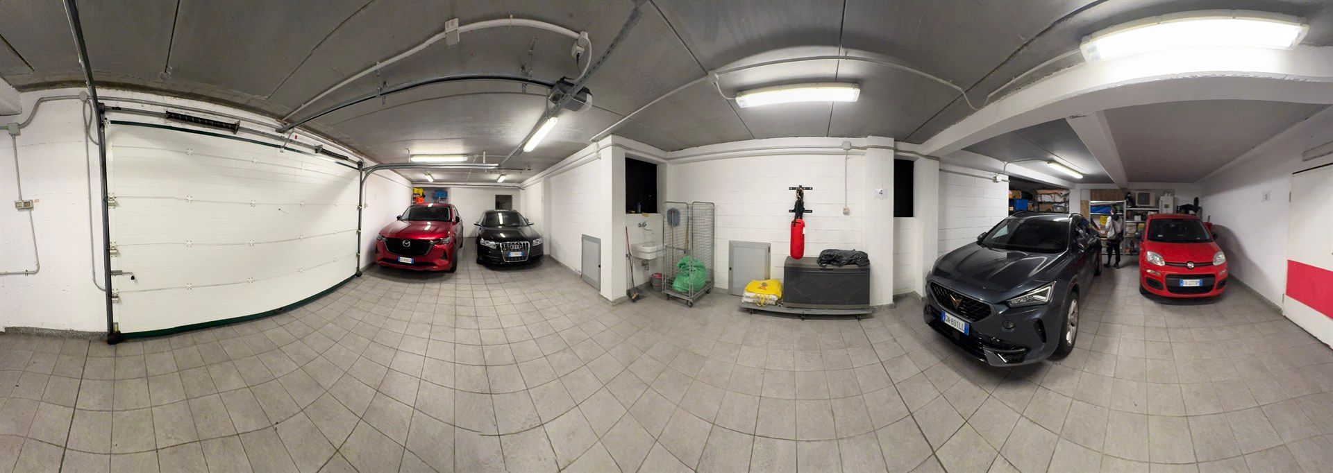 A panoramic view of a garage with cars parked in it.