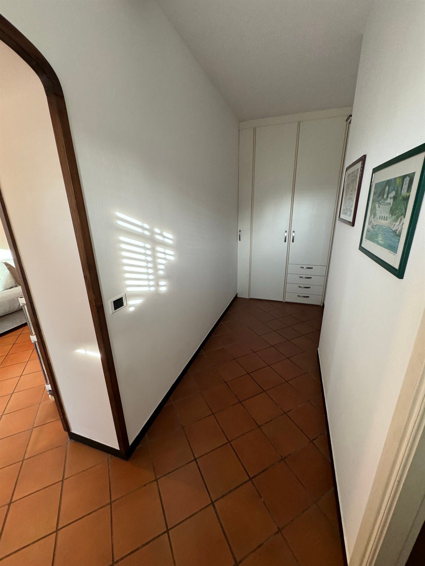A hallway with a tiled floor and a white wall