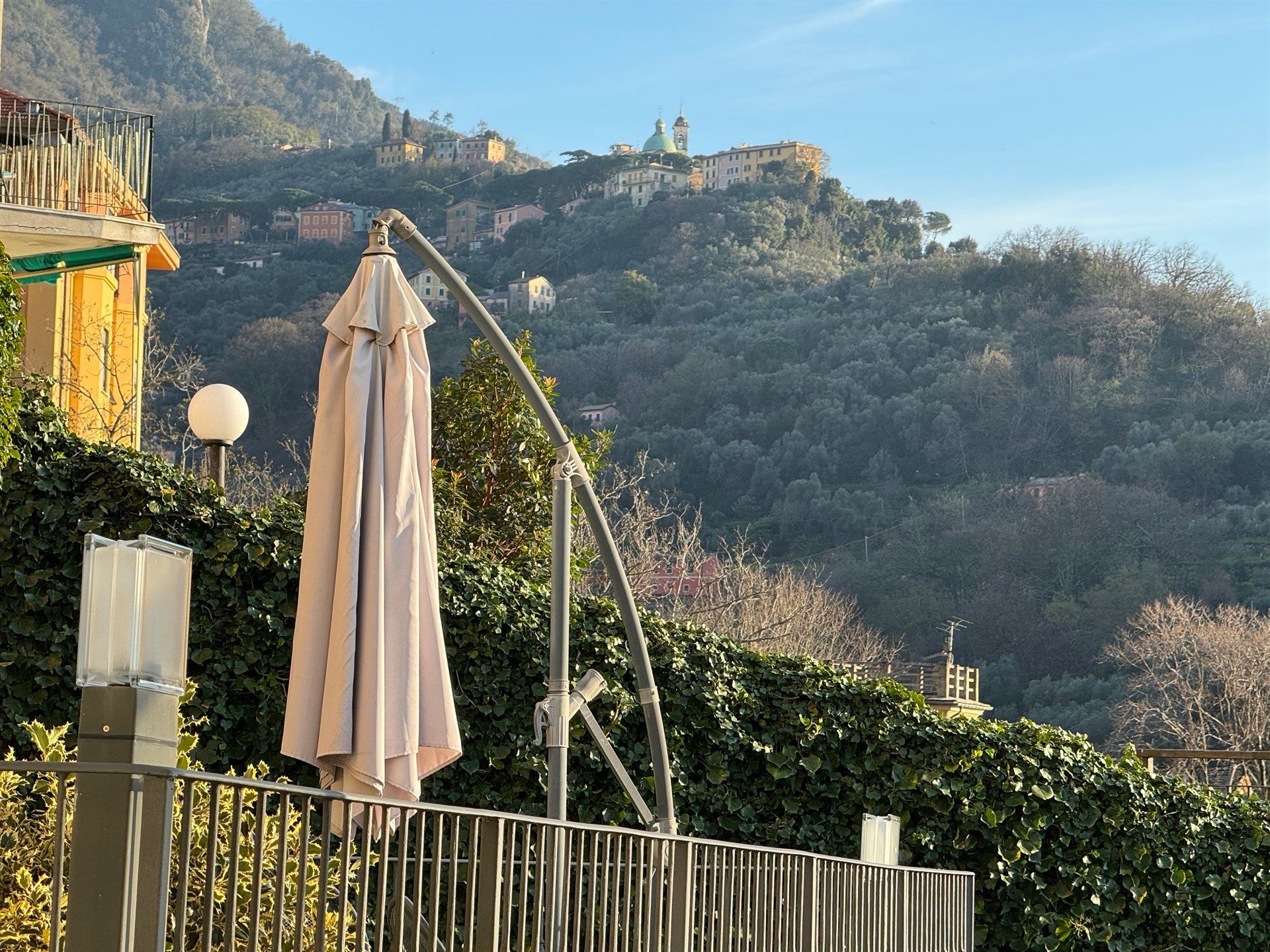 An umbrella is hanging over a fence with a mountain in the background