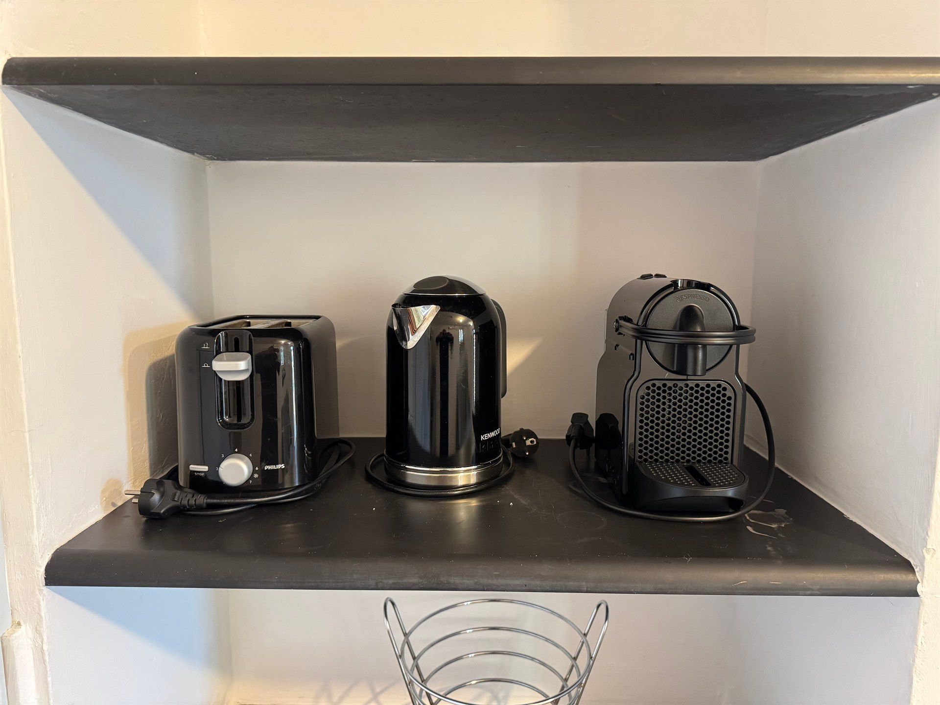 Three black appliances are sitting on a black shelf.