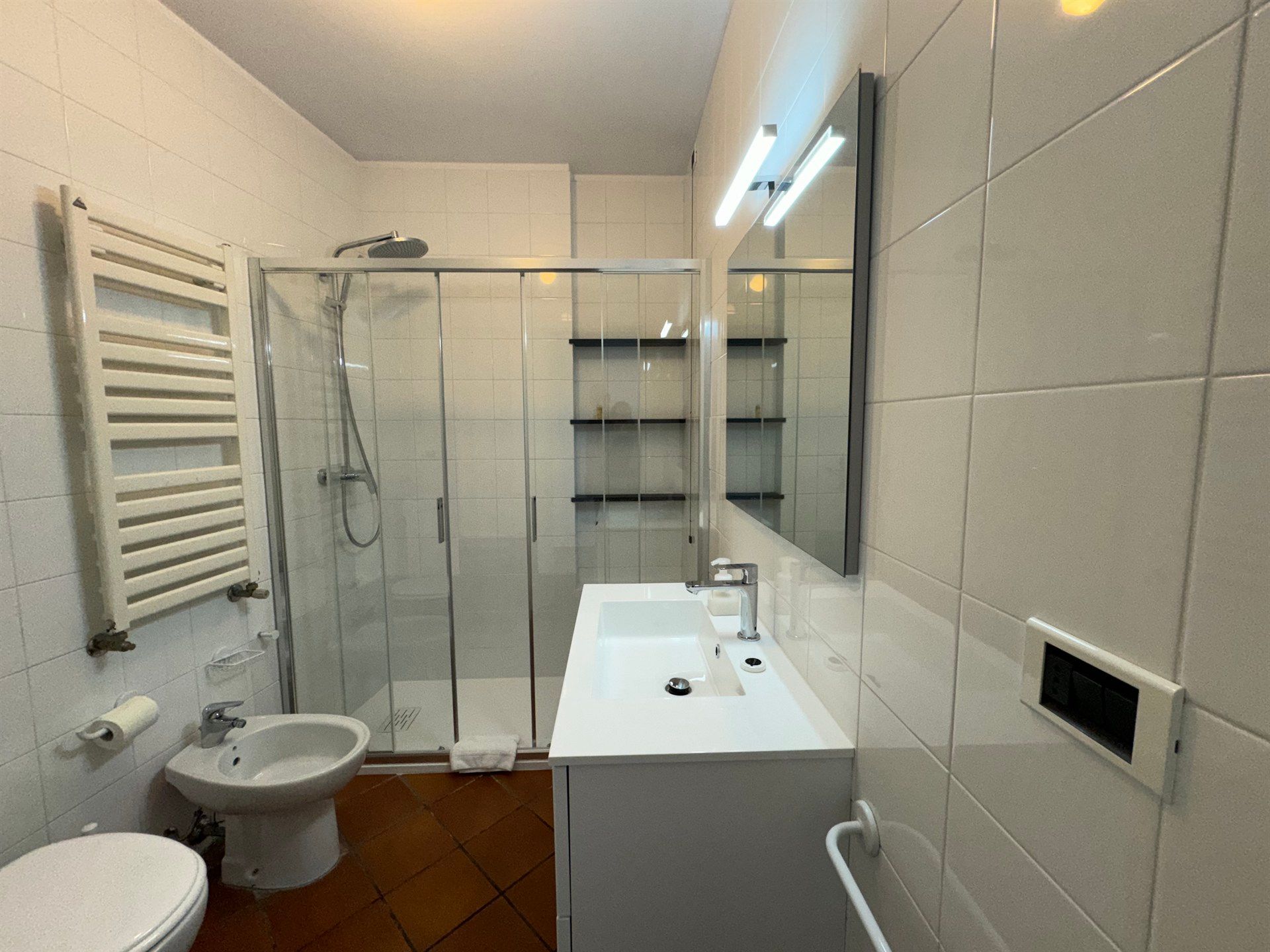 A bathroom with a toilet , sink , shower and mirror