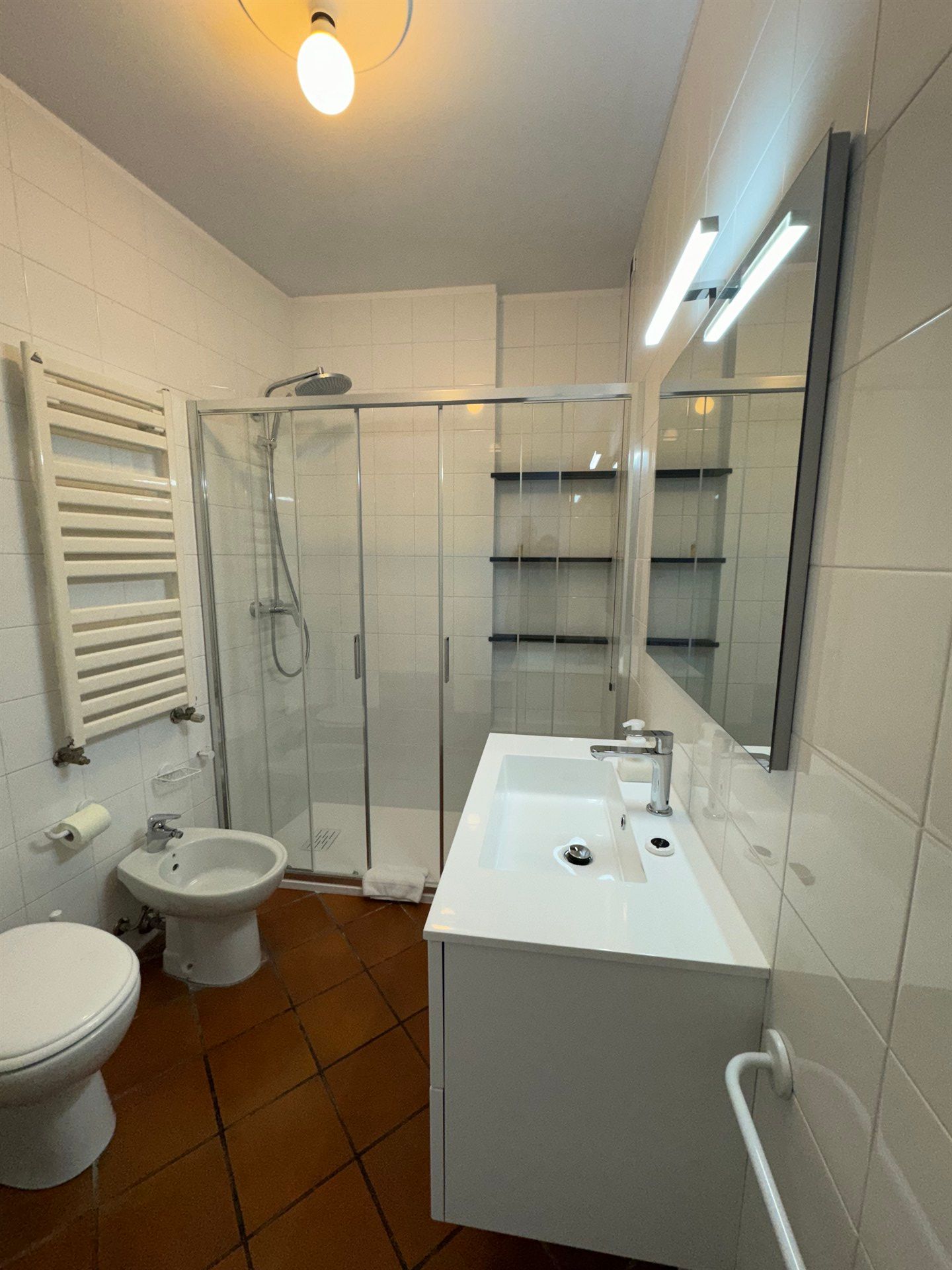 A bathroom with a toilet , sink , shower and mirror.
