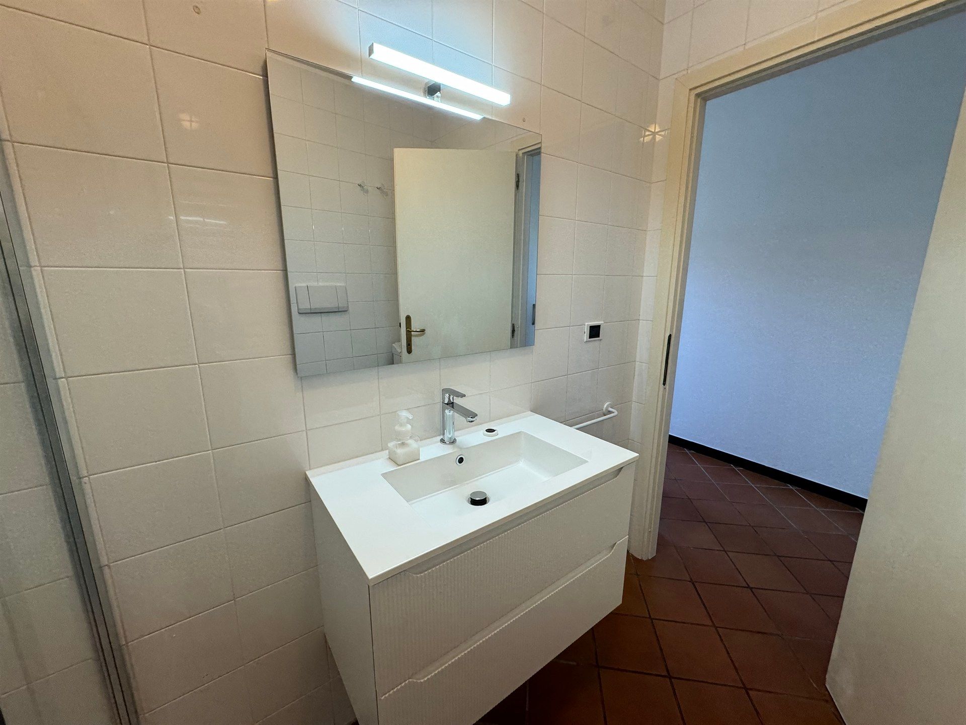 A bathroom with a sink , mirror and door.
