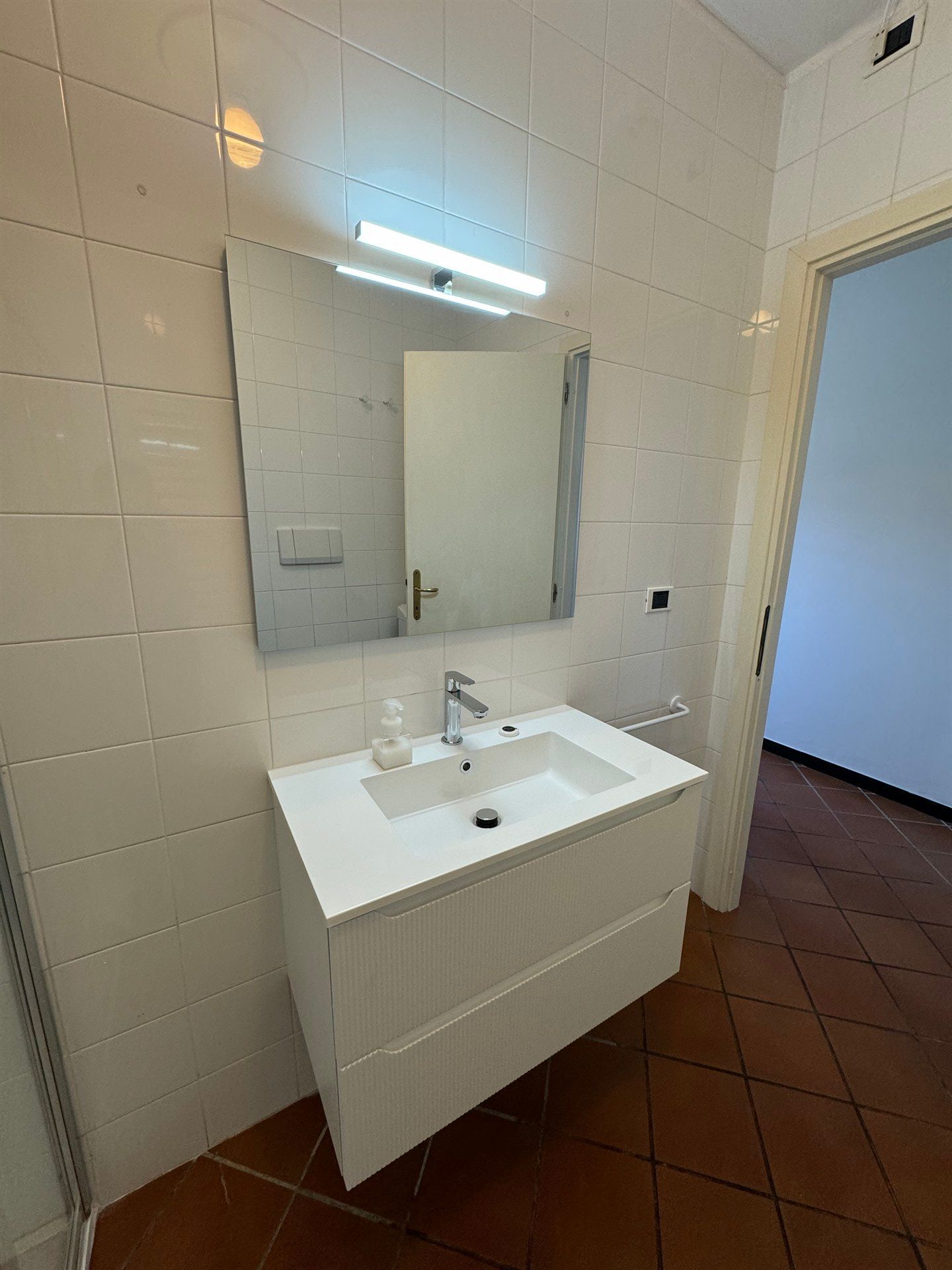 A bathroom with a sink , mirror and door.