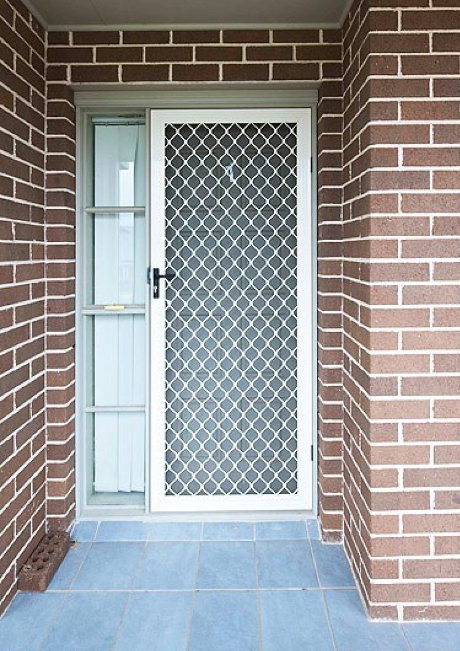 A brick wall with a white door and a blue tile floor.