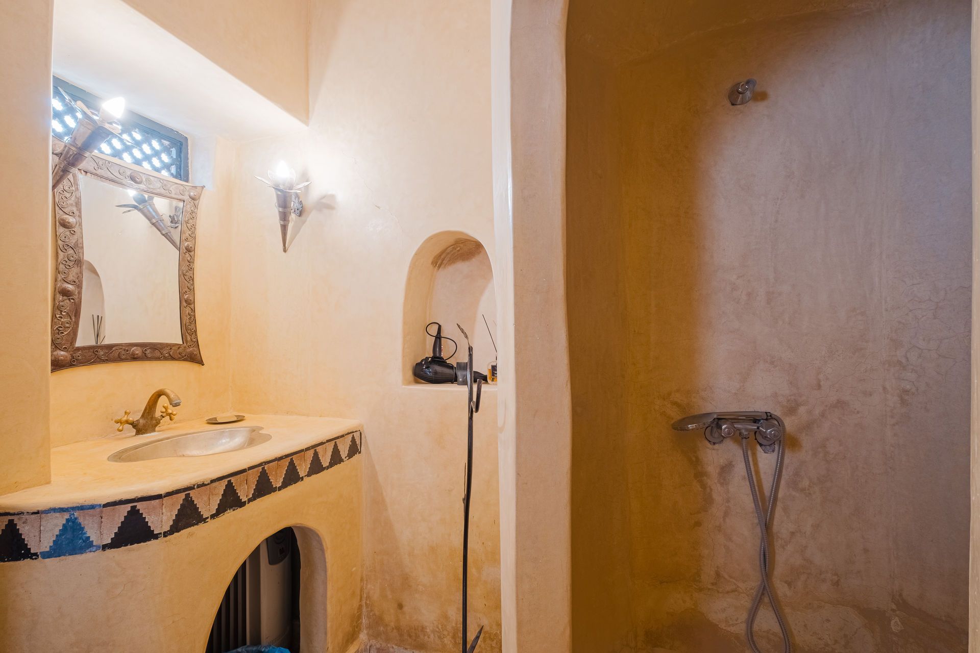 Bathroom with tan walls, sink with blue and white tile trim, and an arched shower.