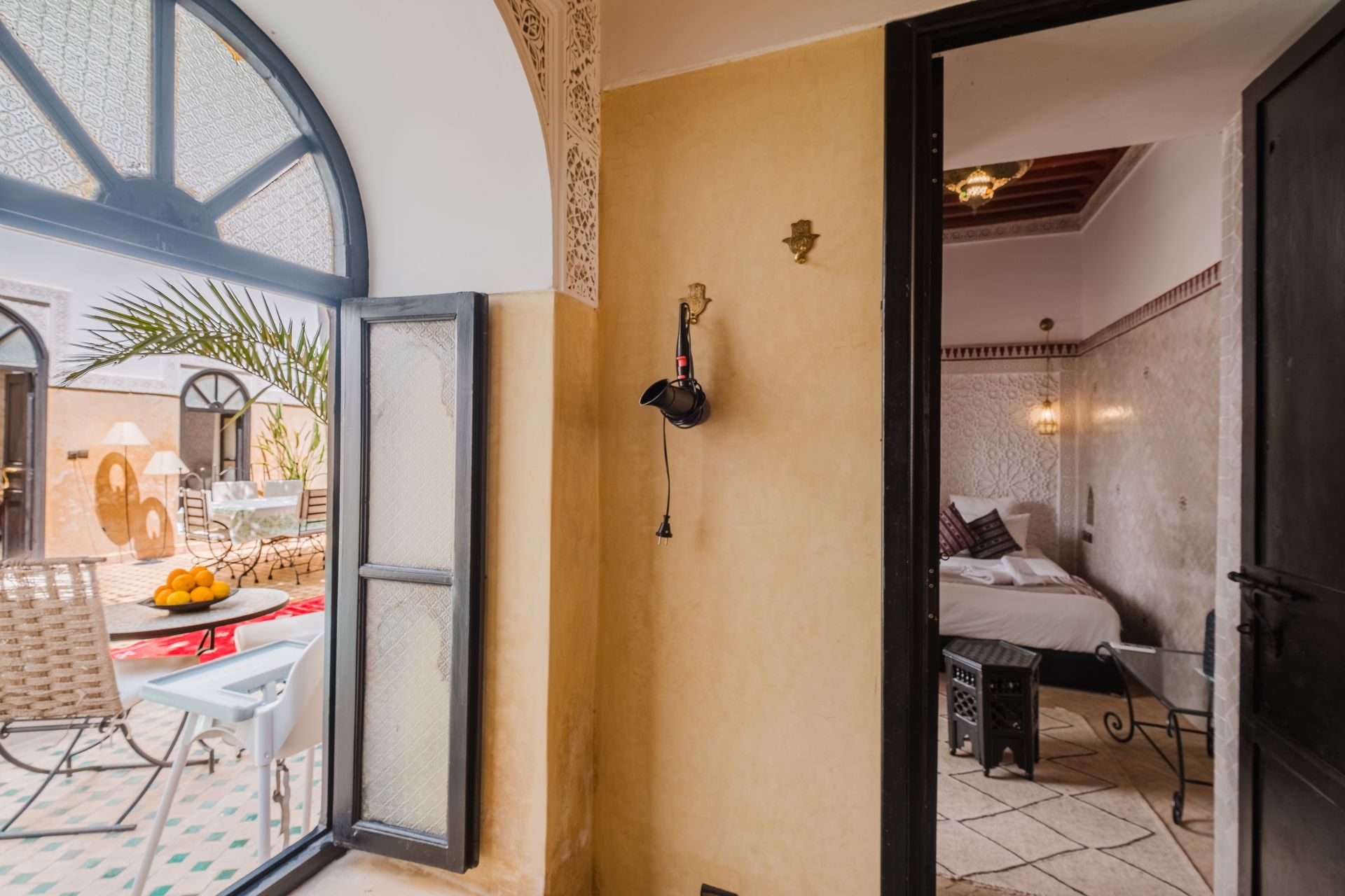 Interior view: doorway to bedroom, open window to patio with table, chair, and palm.
