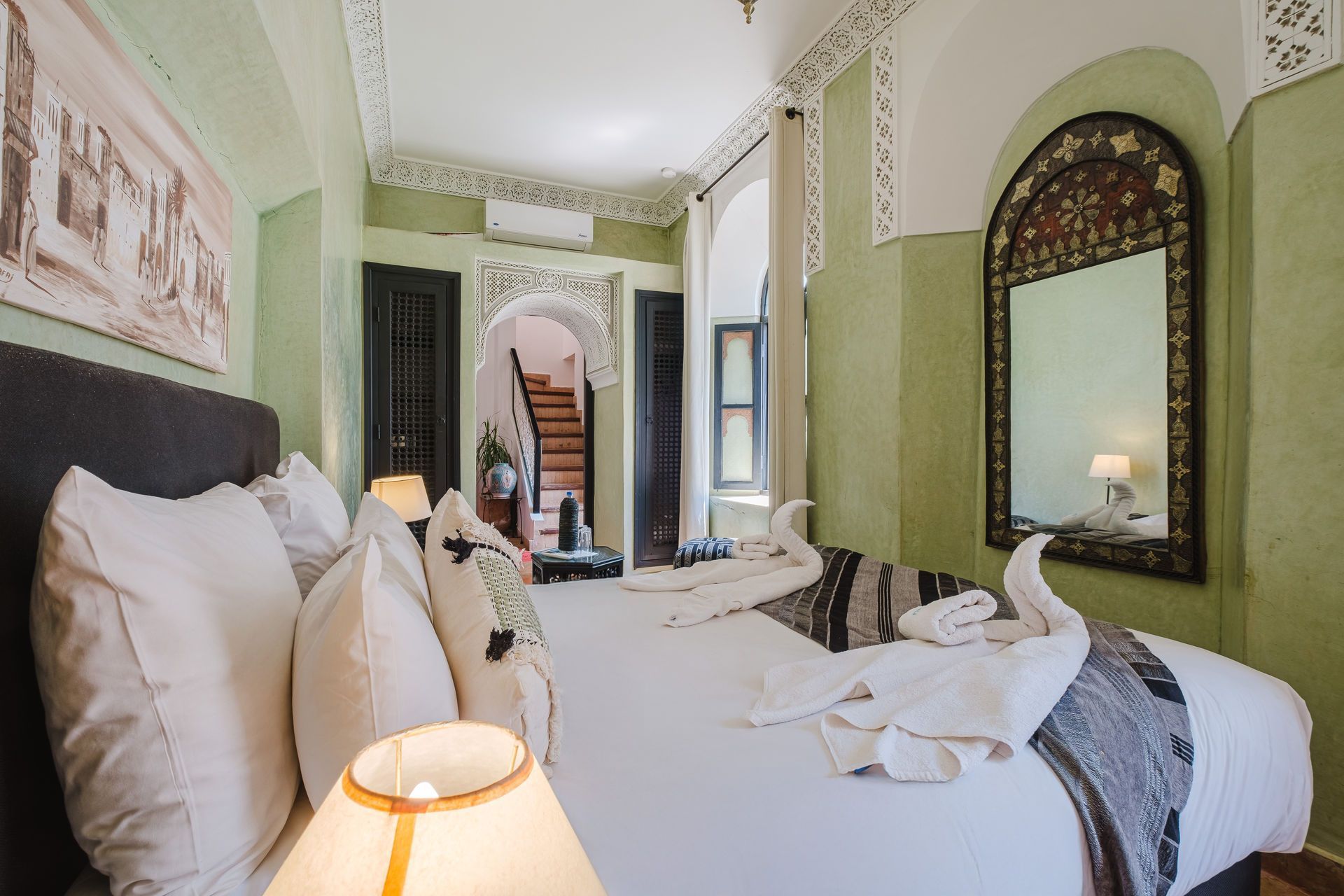 Bedroom with green walls, ornate decor, and a large bed with white linens.