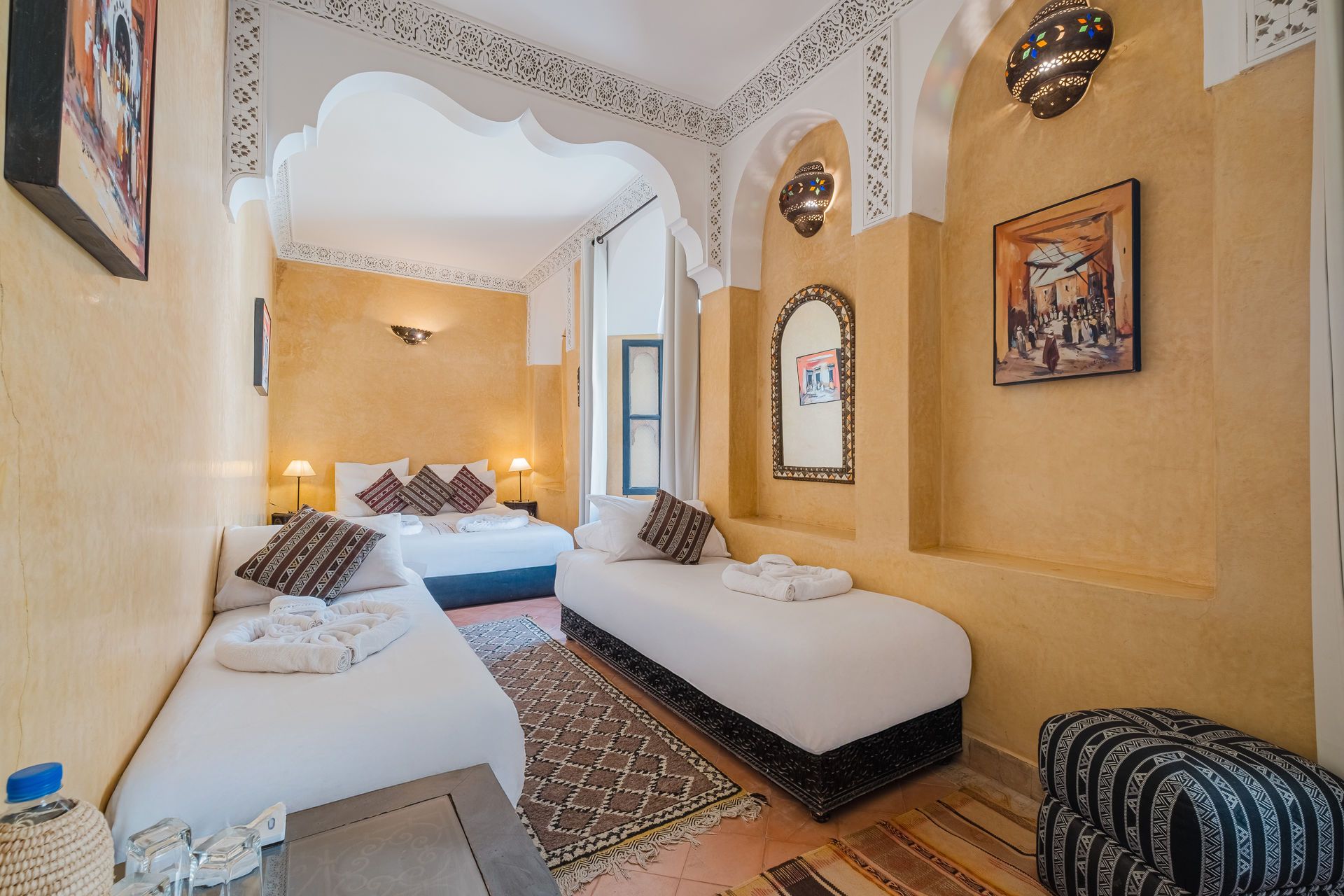 Bedroom with a double and two single beds, Moroccan decor, yellow walls, archways.