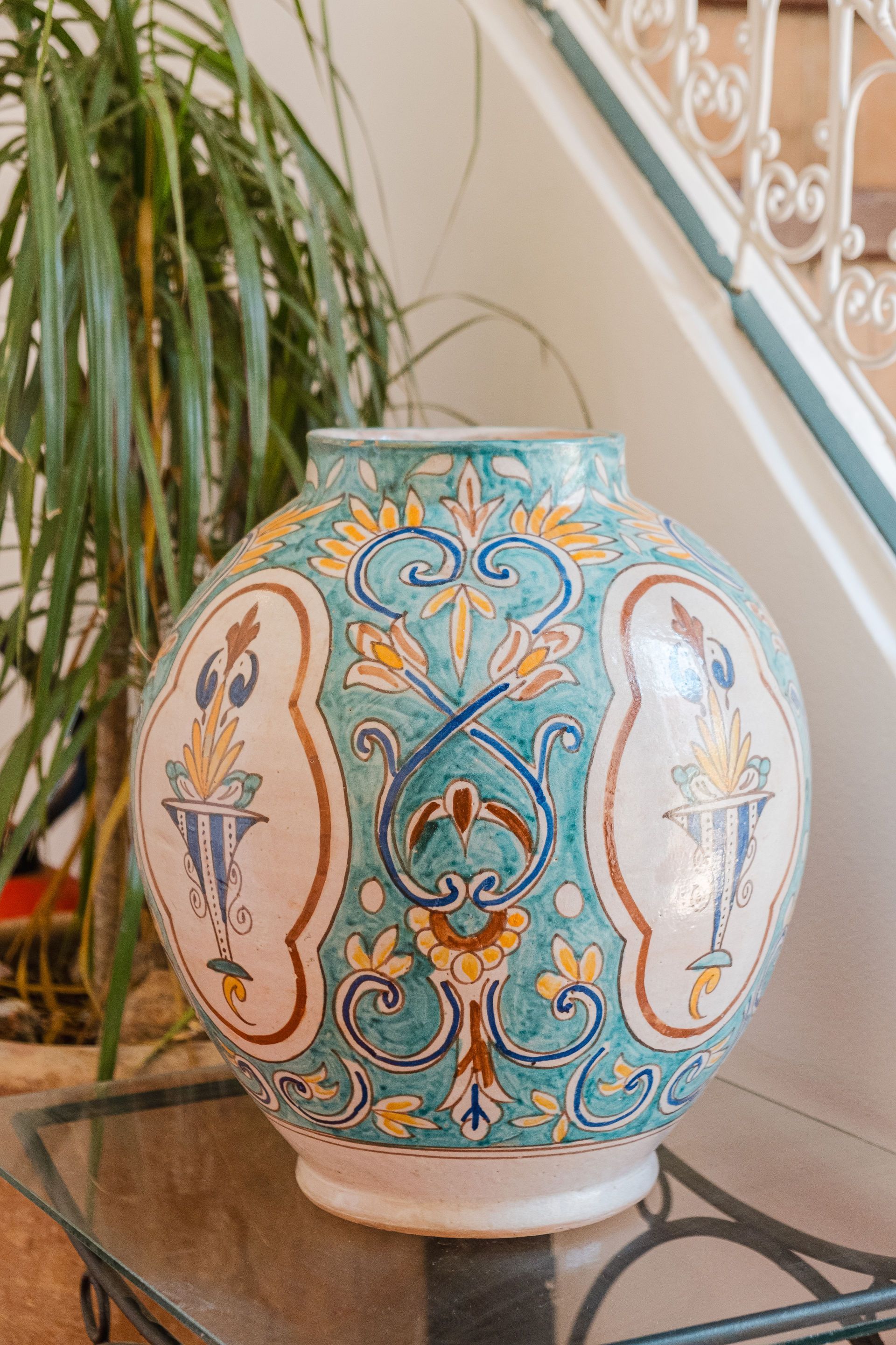 Large, round, decorated ceramic vase with blue, yellow, and brown floral patterns