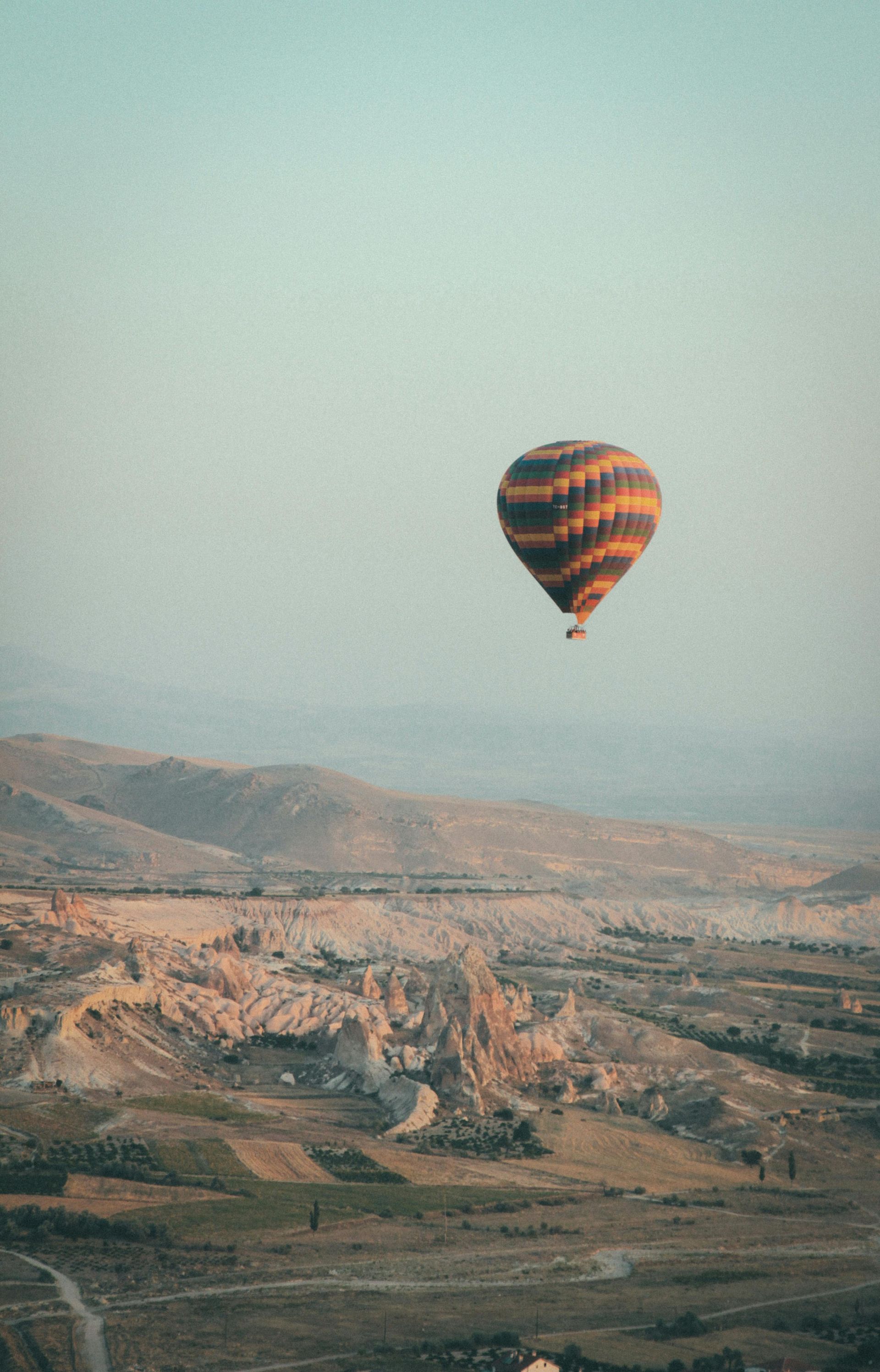 Hot air balloon over Cappadocia's unique rock formations, bathed in early morning light.