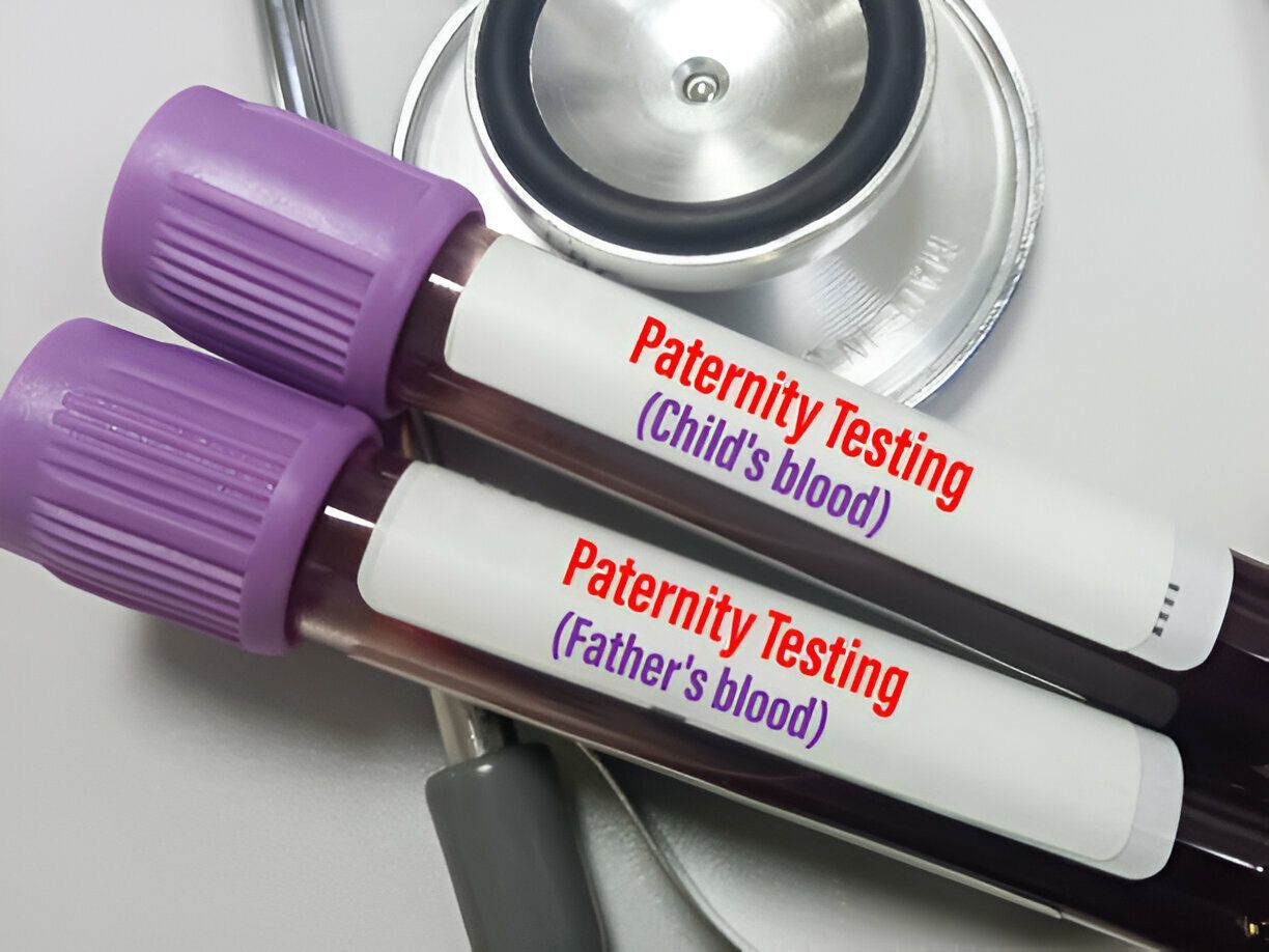 Two labeled blood sample tubes for paternity testing beside a stethoscope.