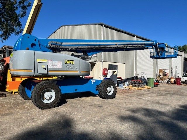 Yellow mobile crane on asphalt against blue sky.