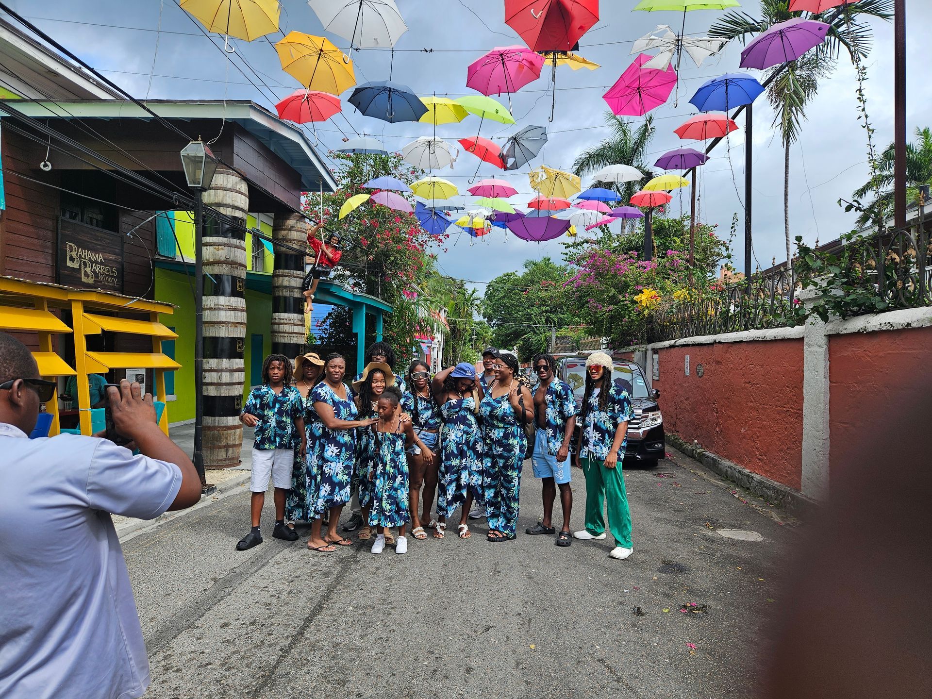 Group of people posing for a photo under colorful umbrellas strung across a street.