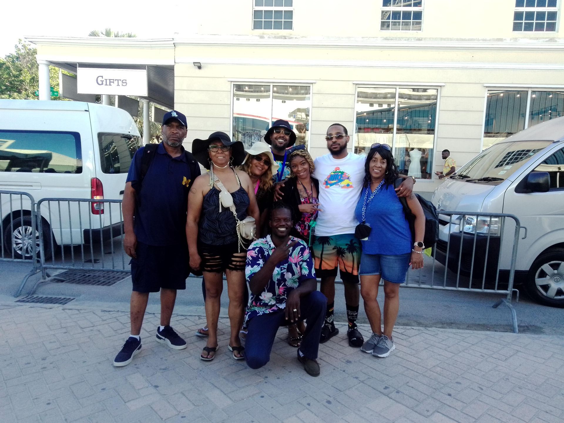 Group of people pose outside a building next to parked vans. Some are smiling, others are looking at the camera.