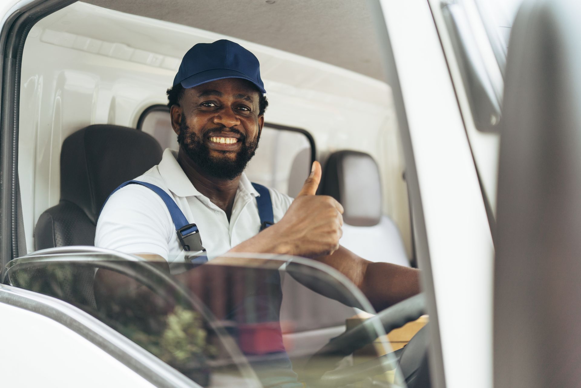 A man is giving a thumbs up while sitting in the driver 's seat of a truck.