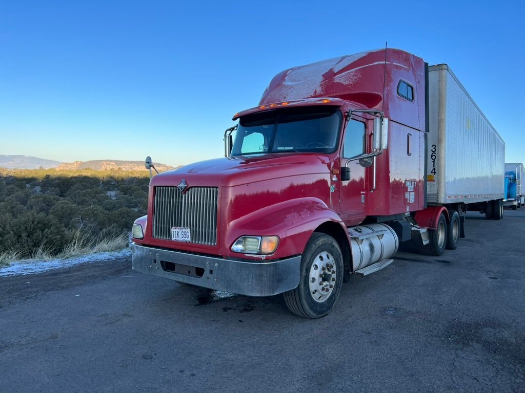 A red semi truck is parked on the side of the road.