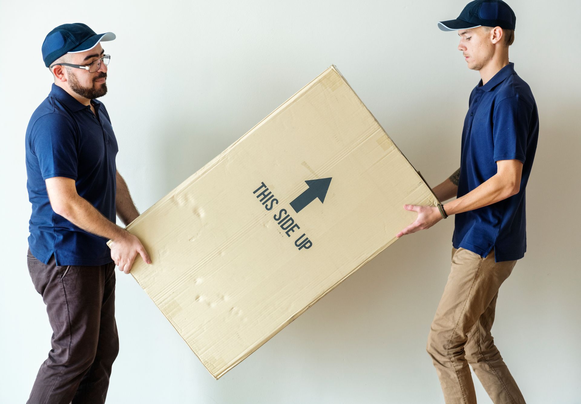 Two men are carrying a large cardboard box.