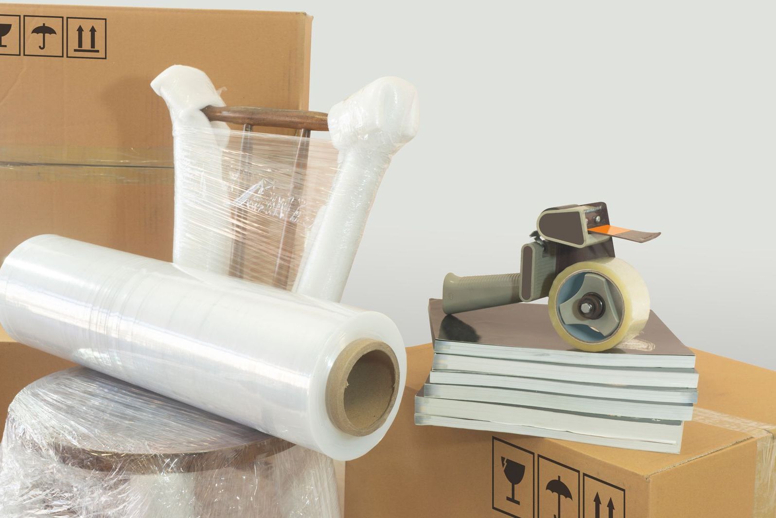 A roll of plastic wrap is sitting on top of a stack of books.