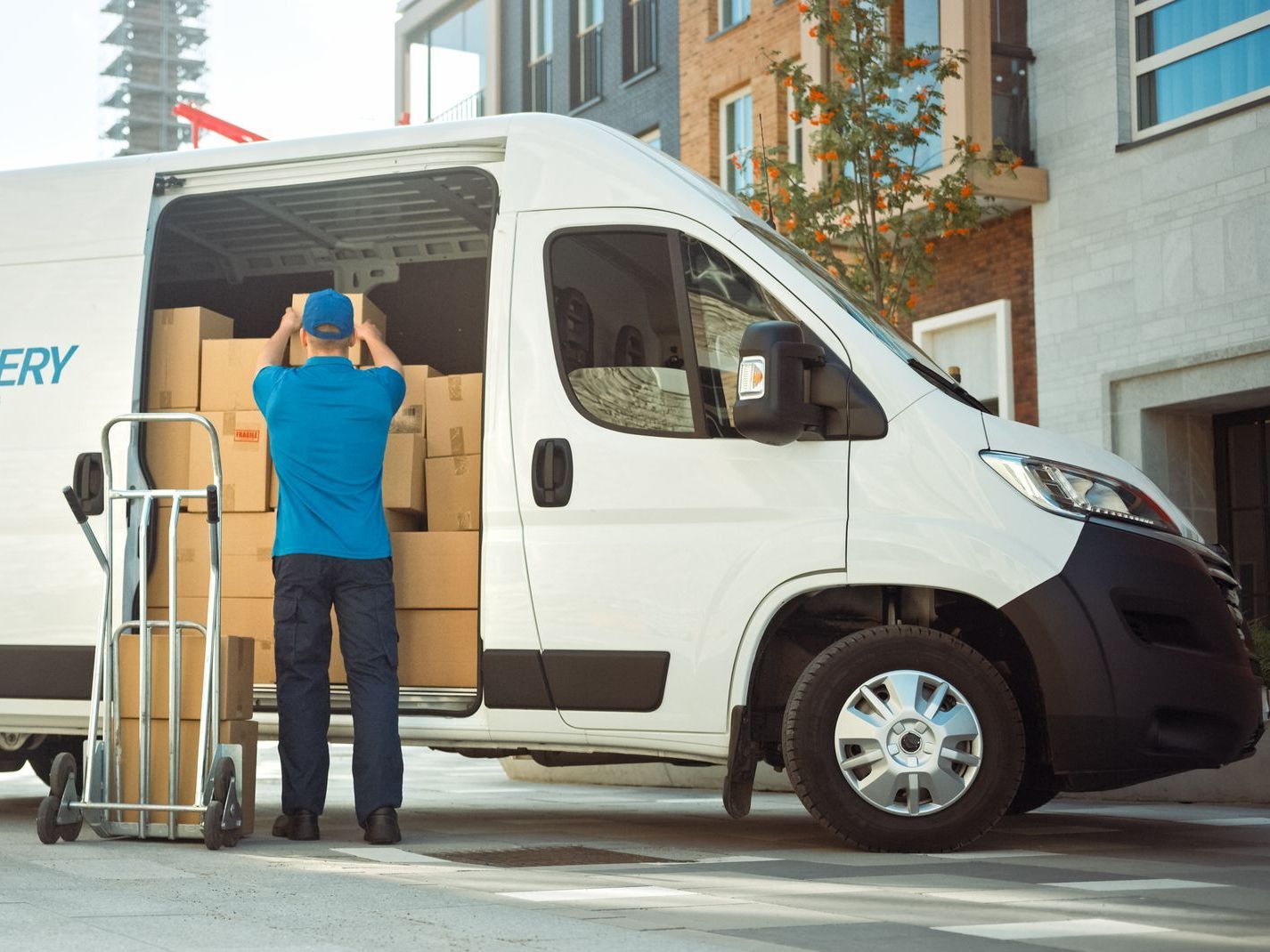 A delivery man is loading boxes into a delivery van.