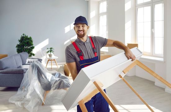 A man is carrying a table in a living room.