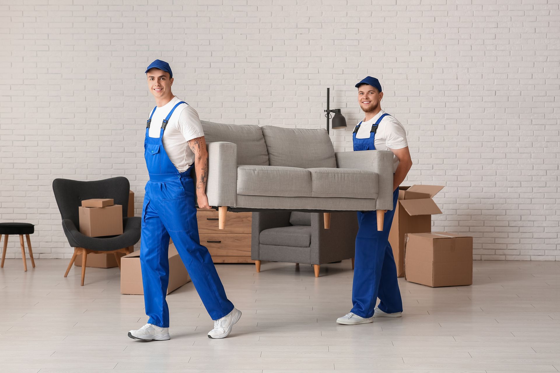 Two movers are carrying a couch in a living room.