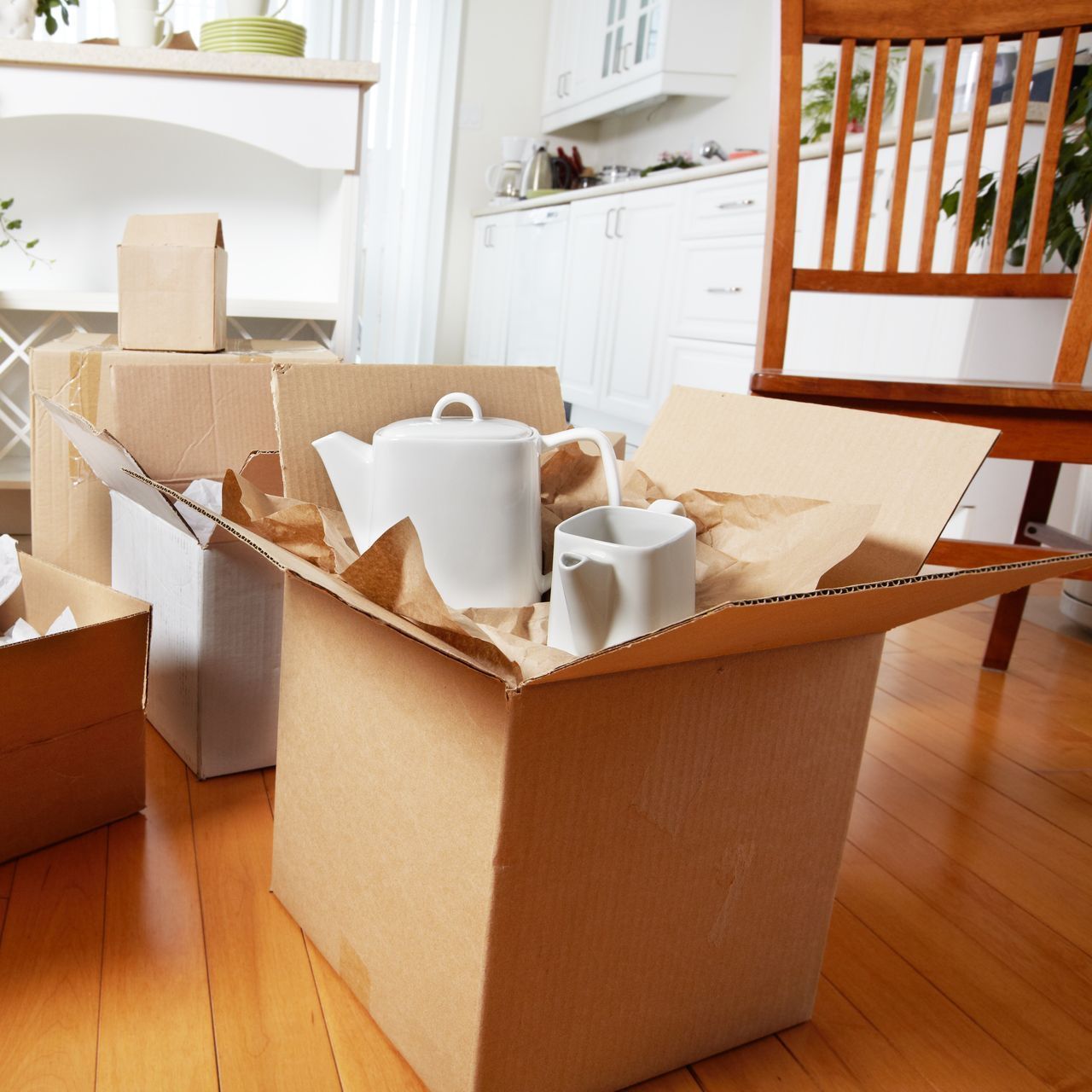 A cardboard box with a teapot and cups in it