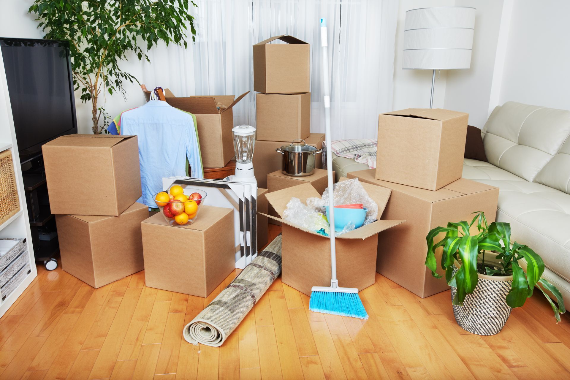 A living room filled with cardboard boxes and a mop