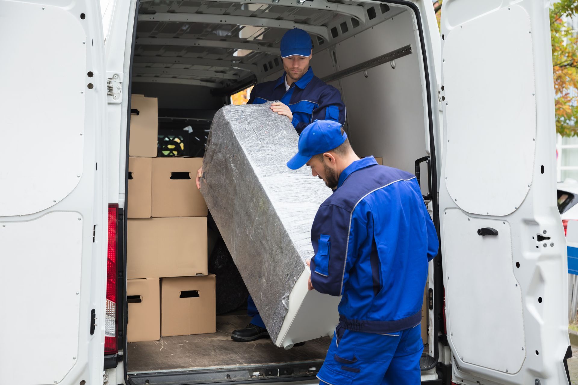 Two men are loading a refrigerator into a van.