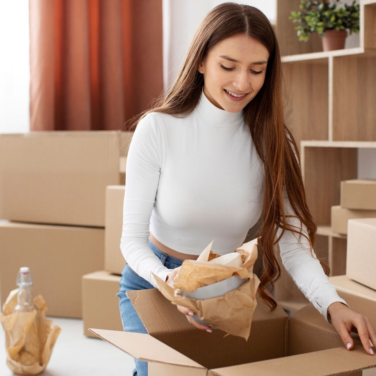 A woman is opening a cardboard box in a living room.