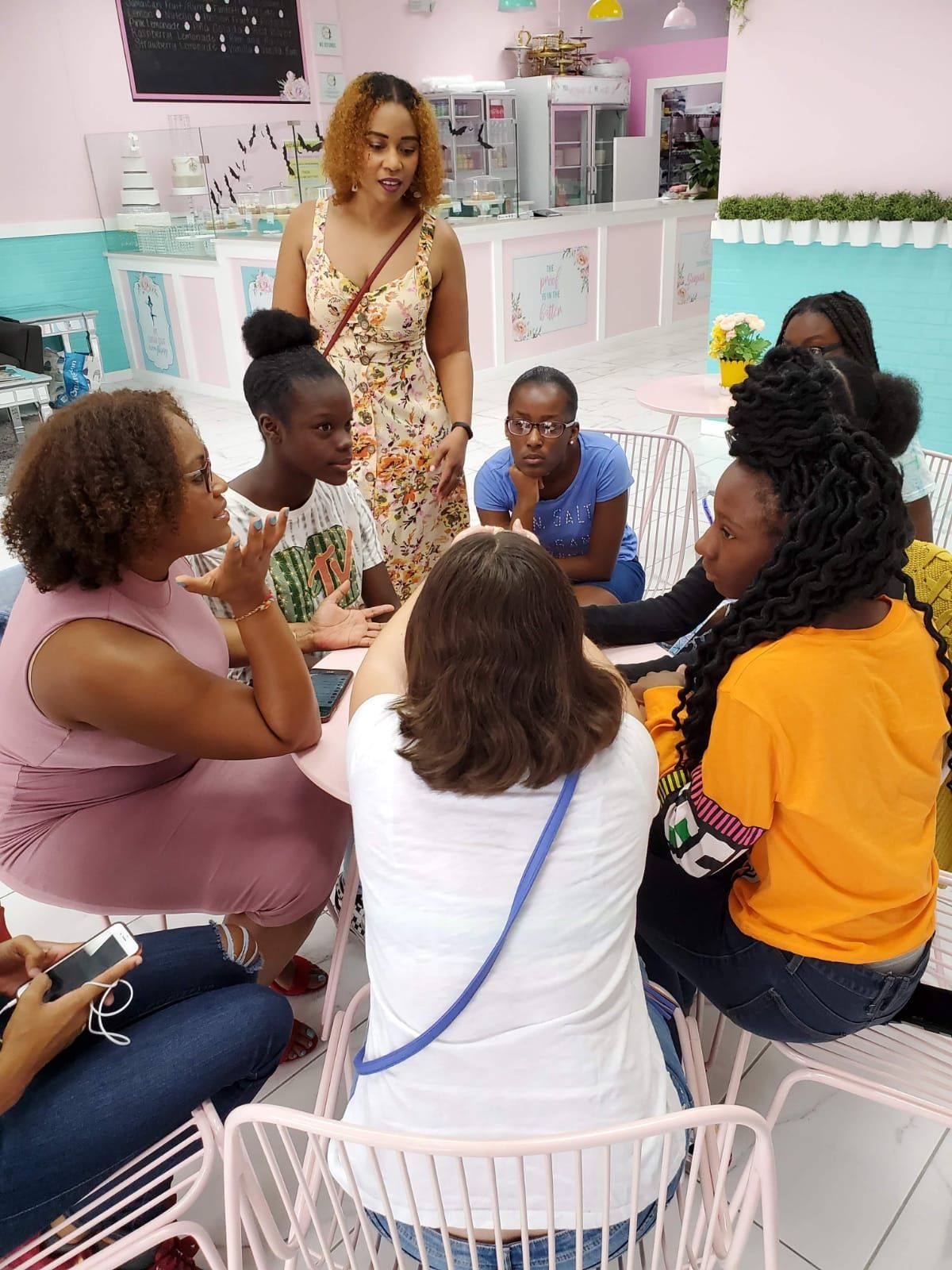 A group of women are sitting around a table talking to each other.