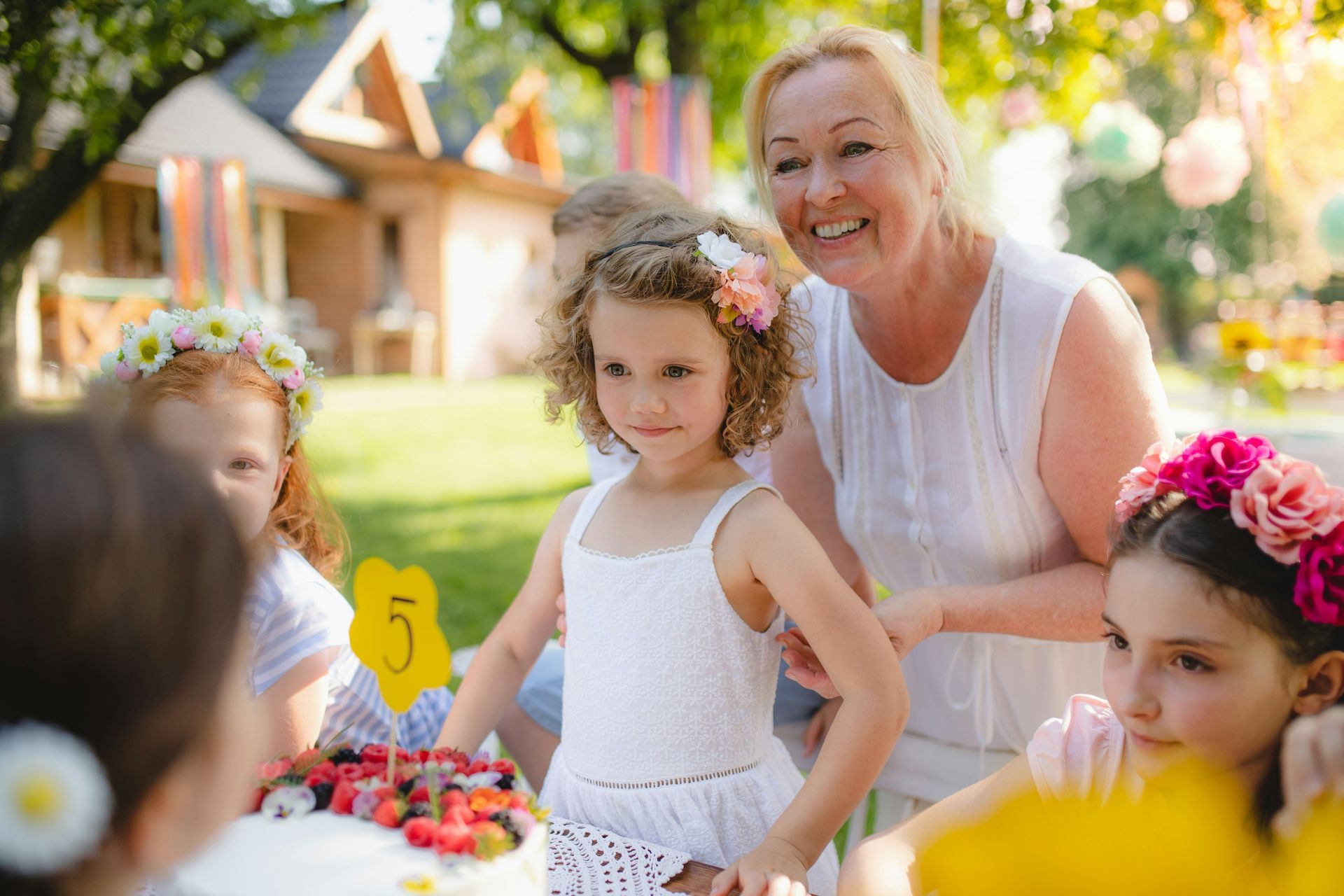 A woman is standing next to a little girl at a birthday party.