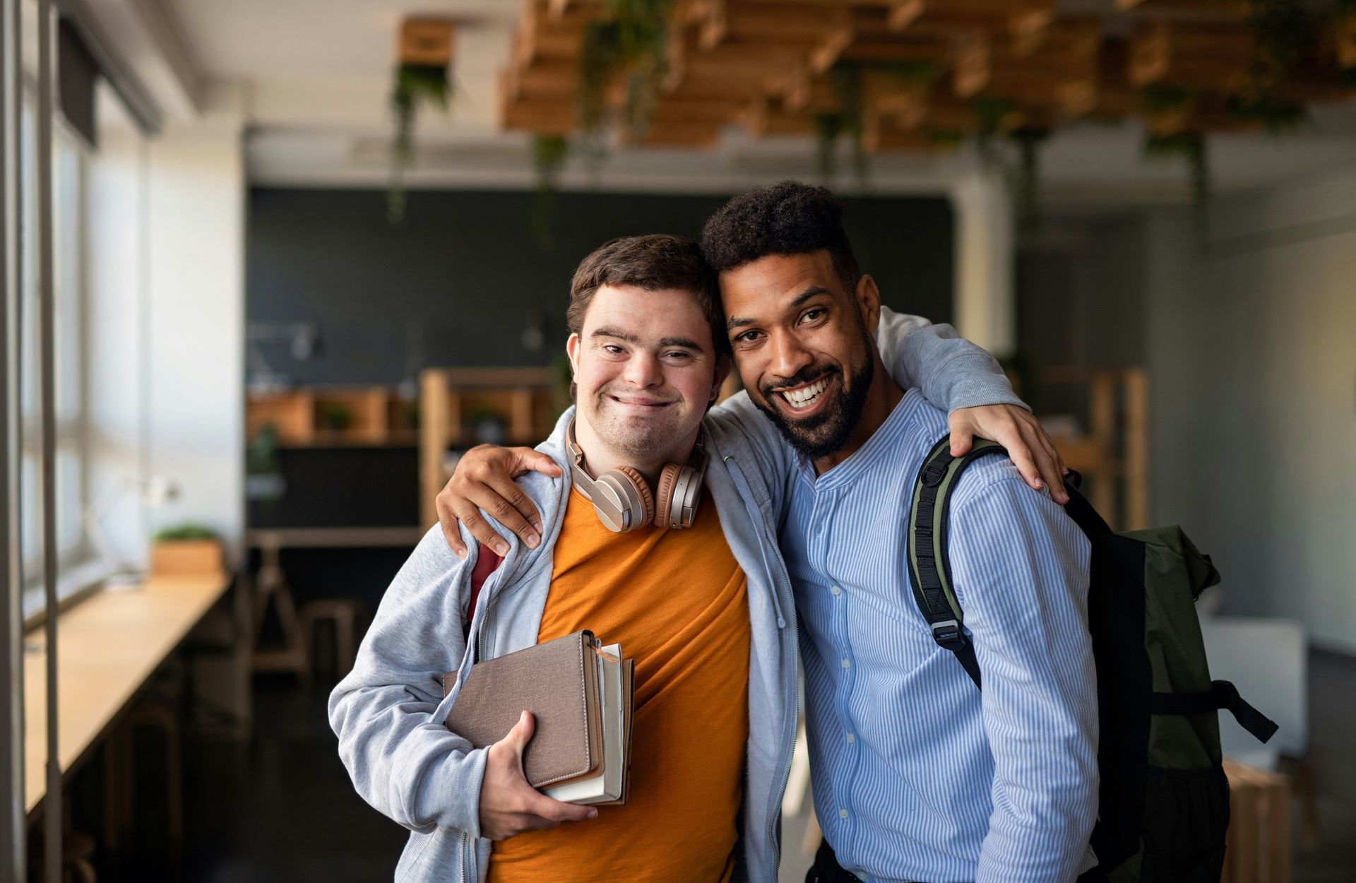 Two men in a classroom. One is holding a book.