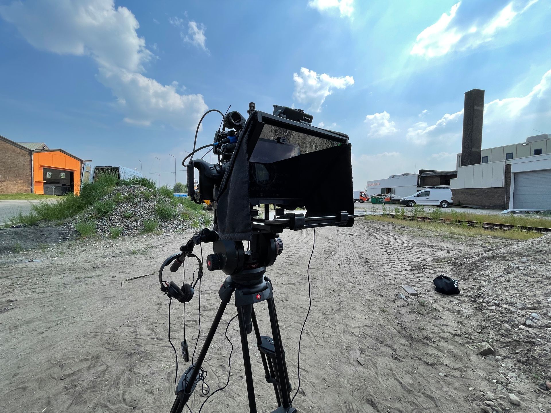 Een camera staat op een statief in een zandveld.