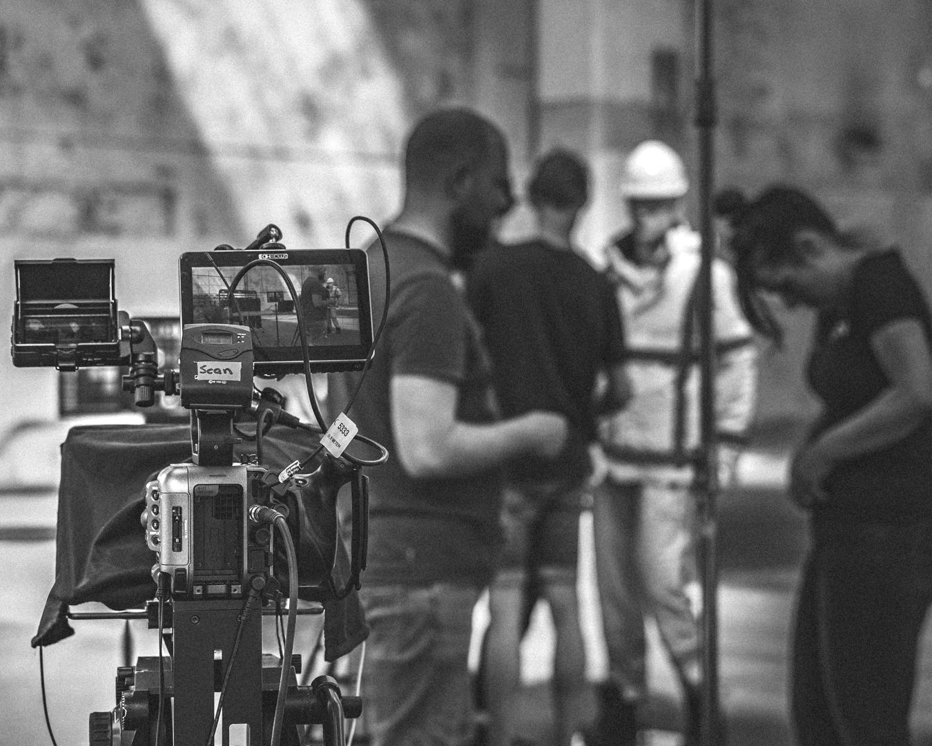 Zwart-witopname van een filmset. De camera is gericht op de crew.