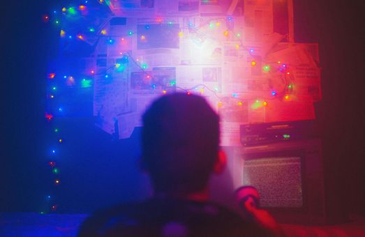 Una persona está sentada frente a una pantalla de proyector con luces navideñas proyectadas en la pared.