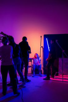 Un grupo de personas está de pie en una habitación con luces moradas y naranjas.