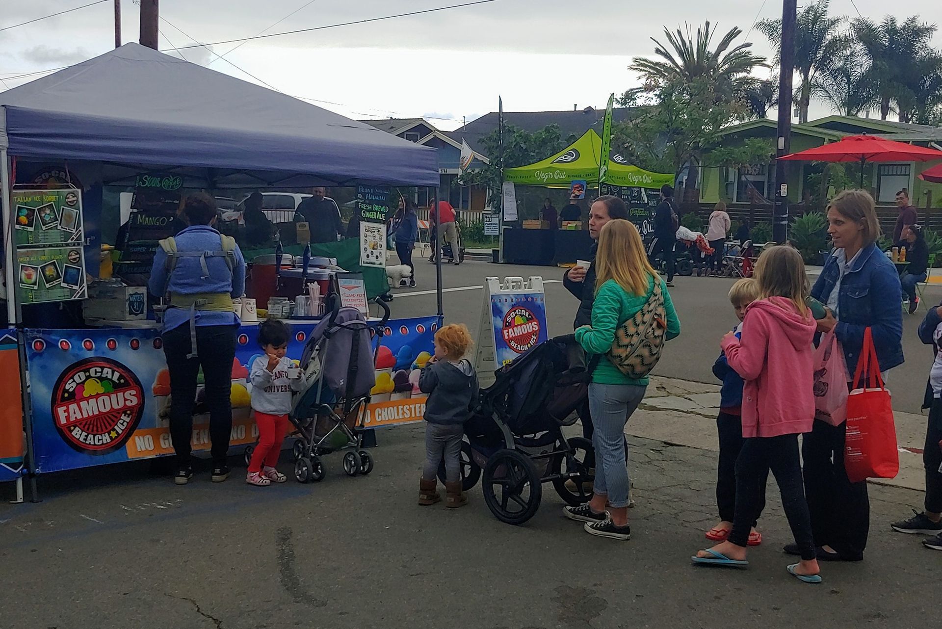 People stand in line at a food stall featuring a blue 