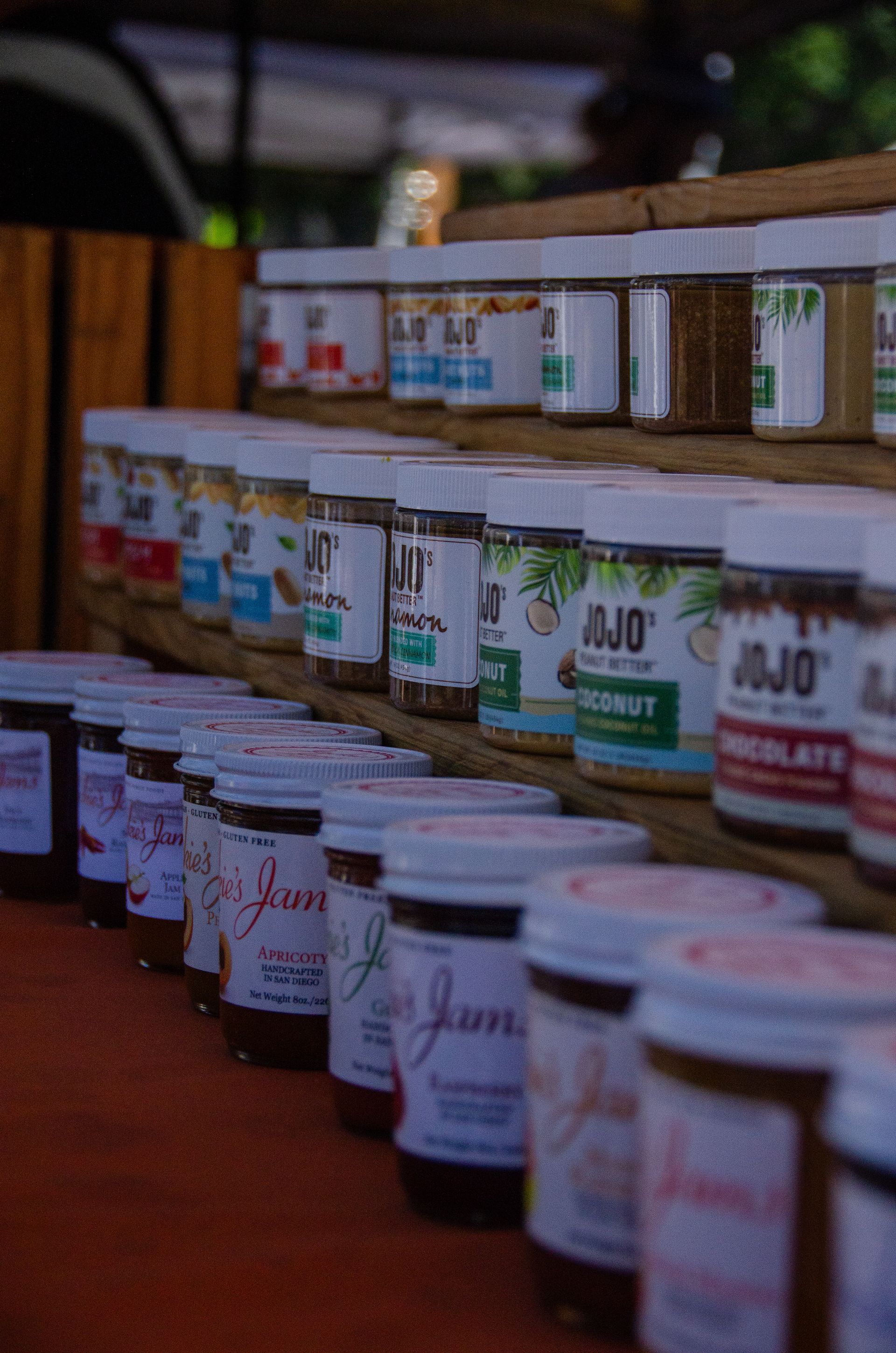 Rows of Jojo brand jars displayed on wooden shelves at a market.